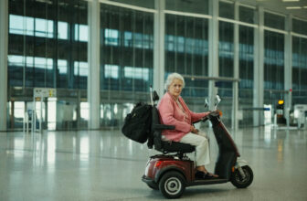 Older woman on a mobility scooter with luggage in an airport terminal