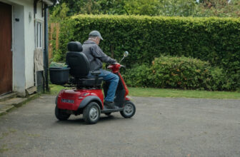 Man riding a well-maintained mobility scooter on a driveway